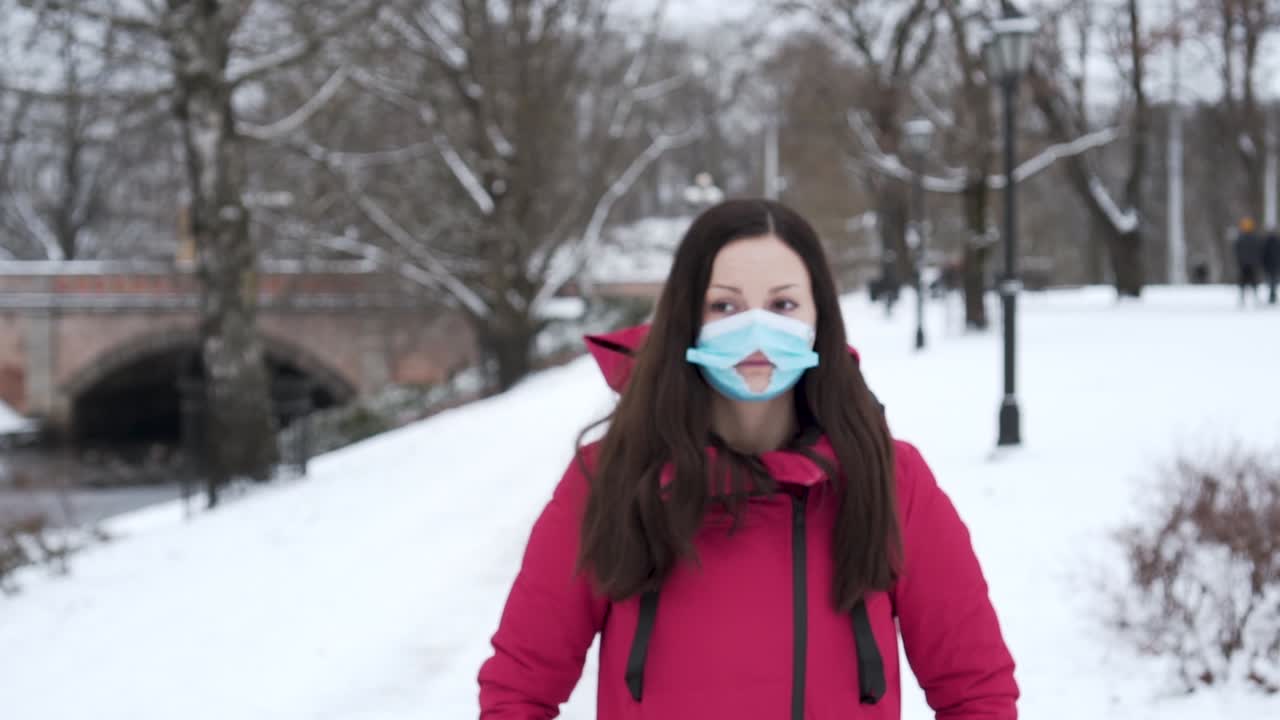 Woman Standing In Snowy City Park Wearing A Face Mask With Hole During Winter