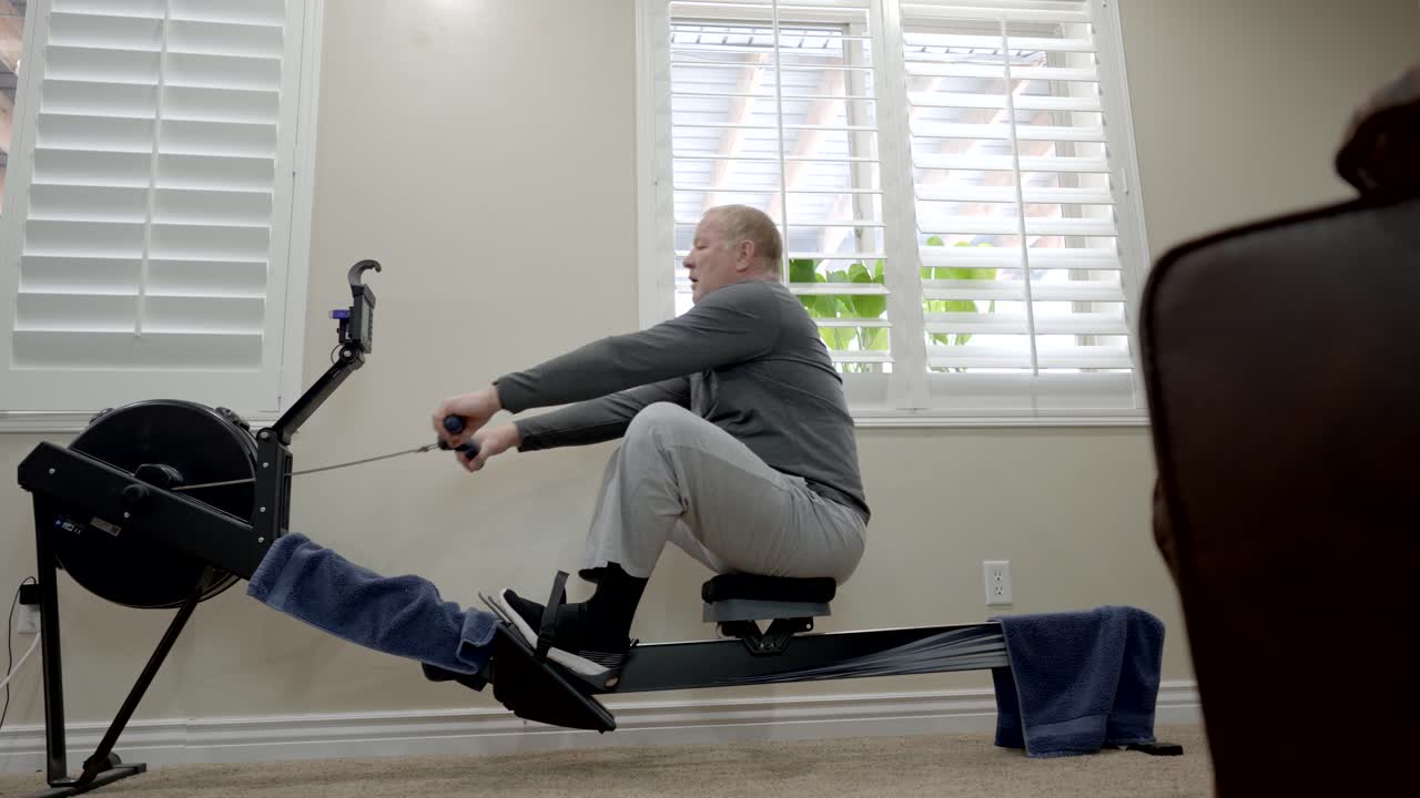 Senior overweight man exercising on a rowing machine ends his workout