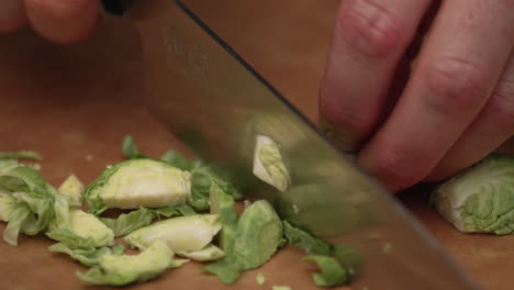 person slicing fresh brussels sprout using kitchen knife