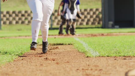 Low-section-of-female-baseball-players-playing-on-the-field,-hitter-running-for-base