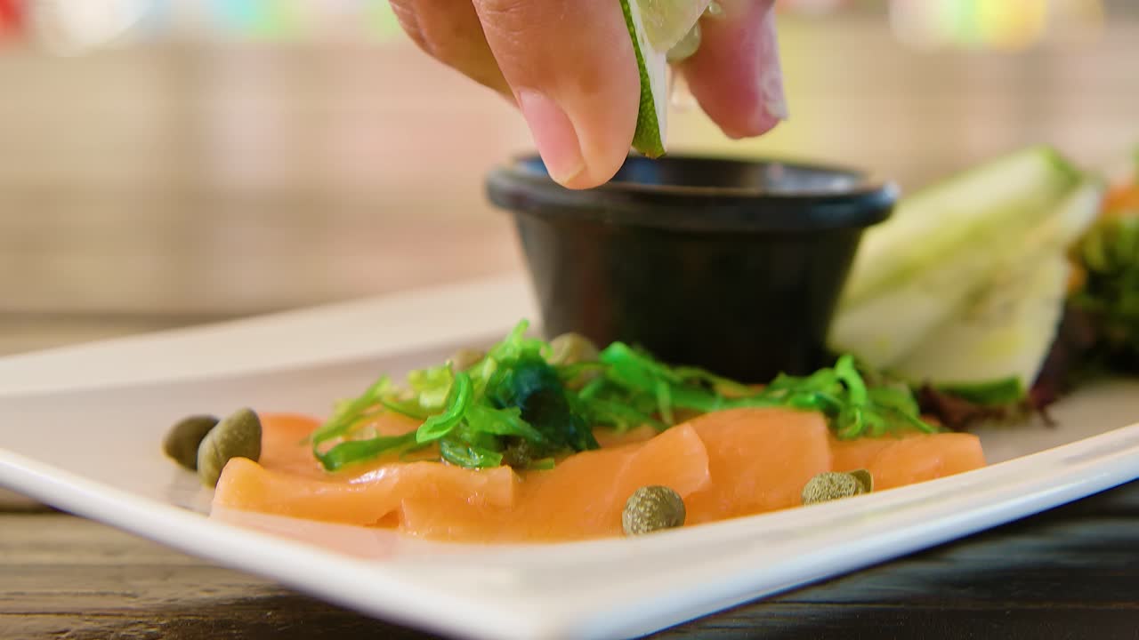 신선한 사시미 연어 위에  ⁇ 을 뿌리고 떨어뜨리며, 느린 움직임으로 손으로 올라갑니다.