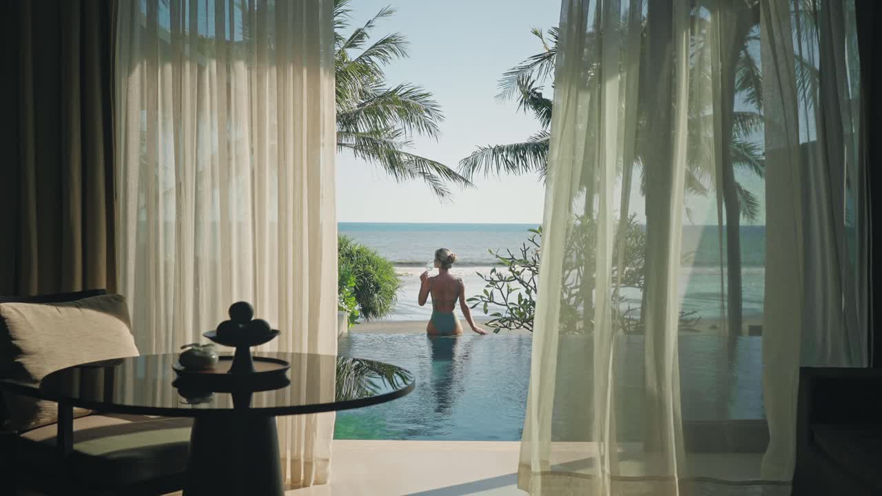 mujer elegante bebiendo vino en el borde de la piscina infinita mirando al mar en bali