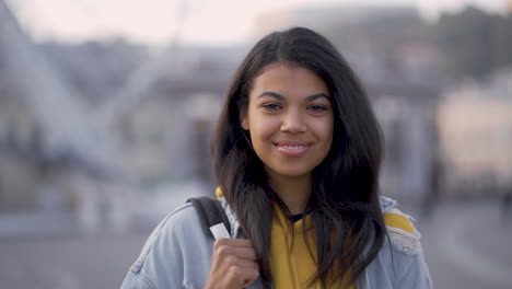 portrait of young pretty black woman smiling and looking at camera outdoors