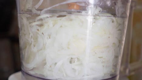 primer plano en cámara lenta de un procesador de alimentos cortando cebolla