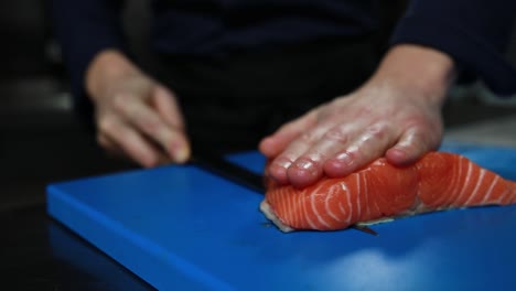 el chef está preparando salmón para el sashimi.