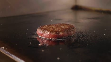 4k slow motion shot of frying cutlet for burger on electric commercial grill.