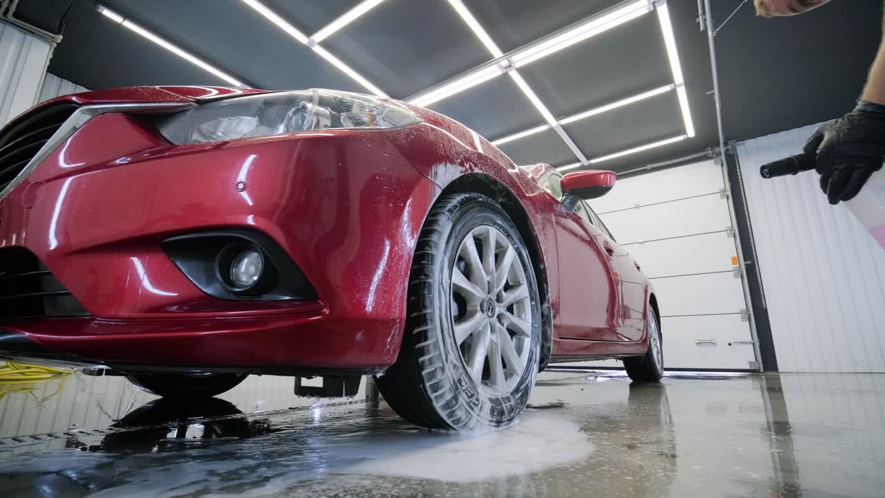lavado de automóviles limpieza con espuma y agua a alta presión. coche rojo