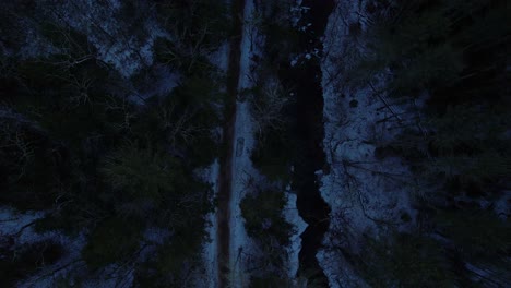 Smooth-nighttime-drone-footage-of-a-beautiful-road-through-a-snowy-winter-forest-in-the-Appalachian-mountains-during-winter-in-New-York's-Hudson-Valley-in-the-Catskill-Mountains-sub-range