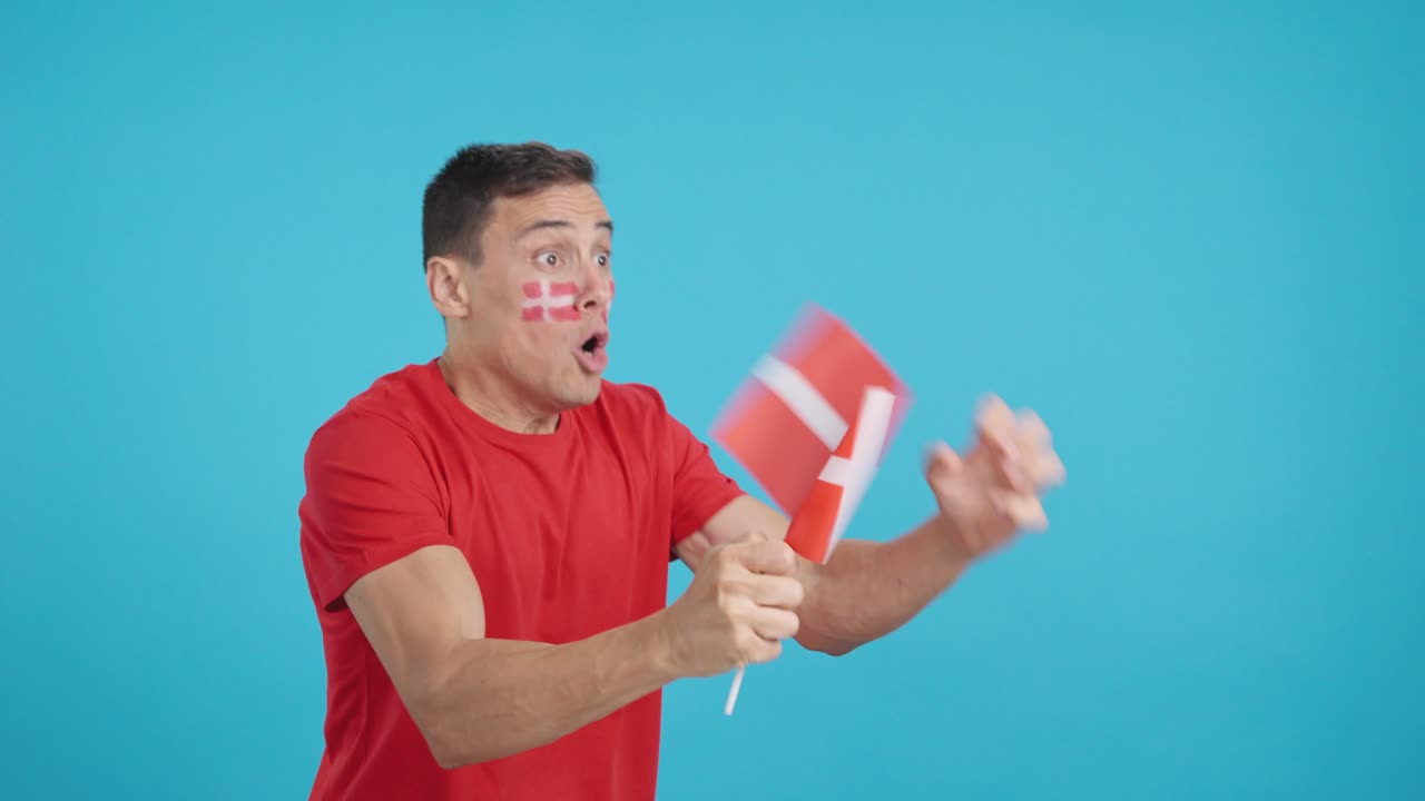 Man cheering for Denmark waving a national flag looking away
