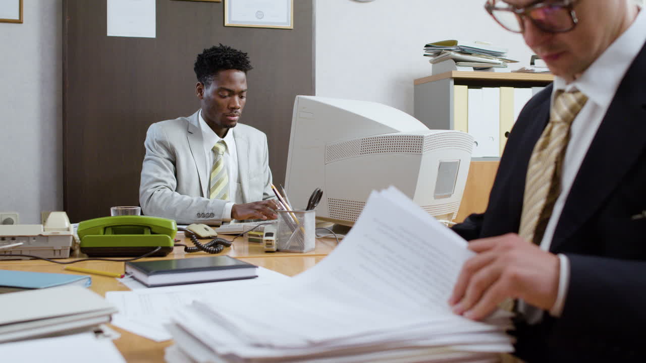 African businessman using retro computer in vintage office.