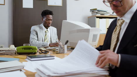 african businessman using retro computer in vintage office.