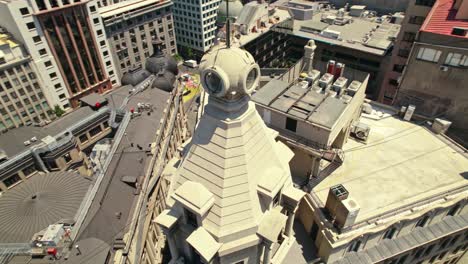 aerial 360 drone around iconic roofs and tower cusp in ariztia building at chile, la bolsa neighborhood, santiago cityscape in summer