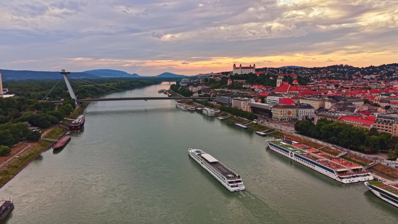 Udsigt over Donau-floden ved solnedgang med både og bylandskab i Bratislava, Slovakiet
