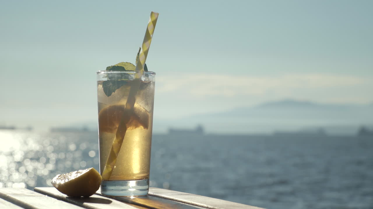 Close up of cold drink being taken from table at beach with ocean background