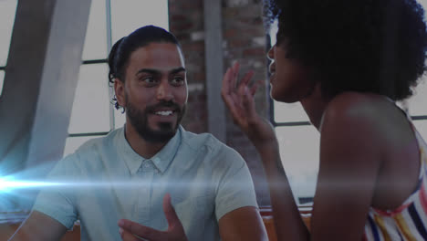 Blue-light-trails-against-african-american-male-and-female-office-colleagues-discussing-at-office