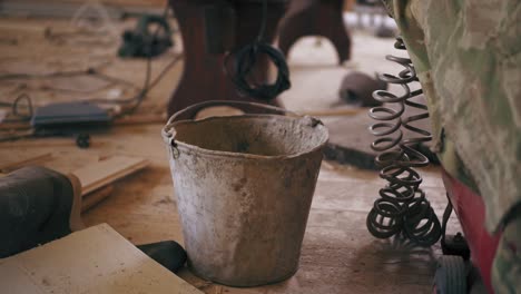 man's hand is taking a metal bucket to start working. repairing room with all the construction materials on the floor.