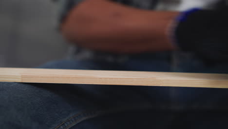 black guy in working gloves polishes wooden plank in shop