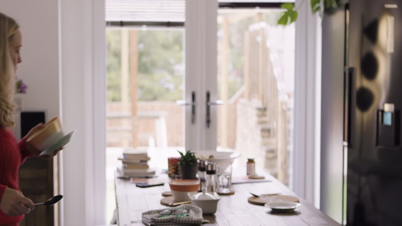 A bright kitchen scene with a woman at the table