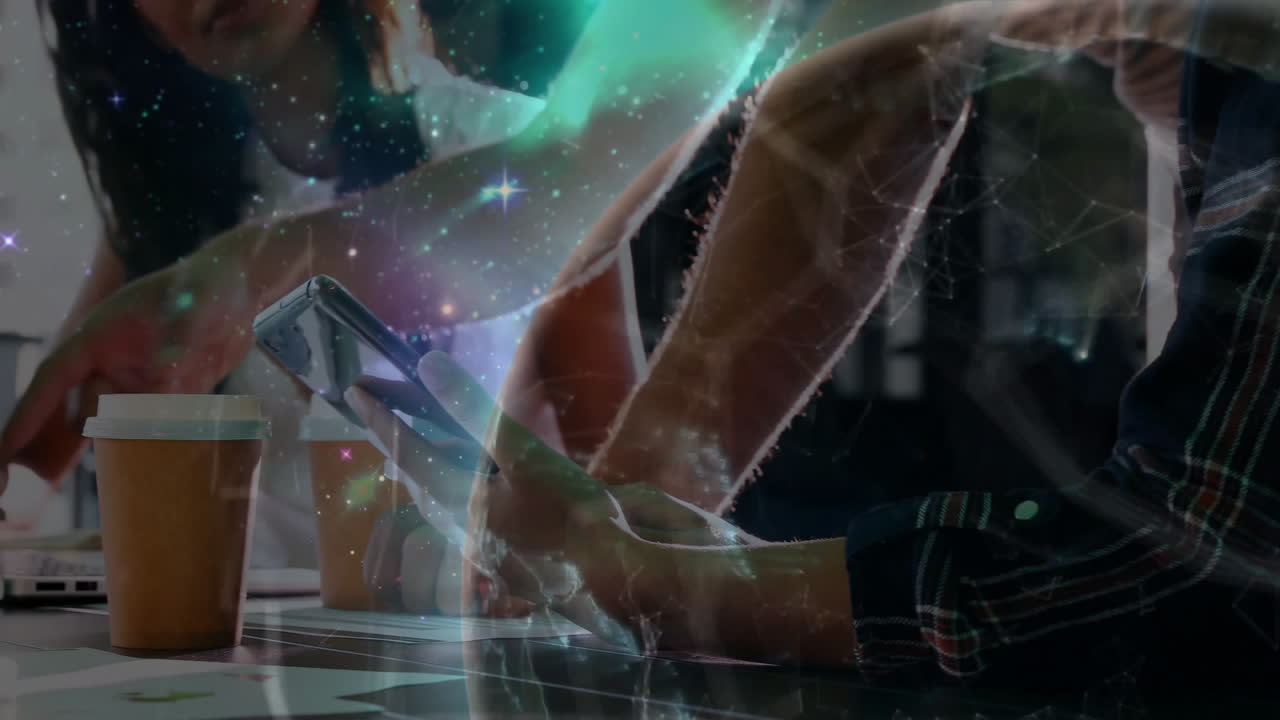 Colleagues collaborating on tech in workspace, showing smartphone, laptop and globe overlay