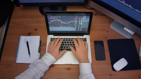 timelapse of business man working hard at desk taking notes on a busy business day. a birdseye view of laptop, notepad, phone and desktop computers.