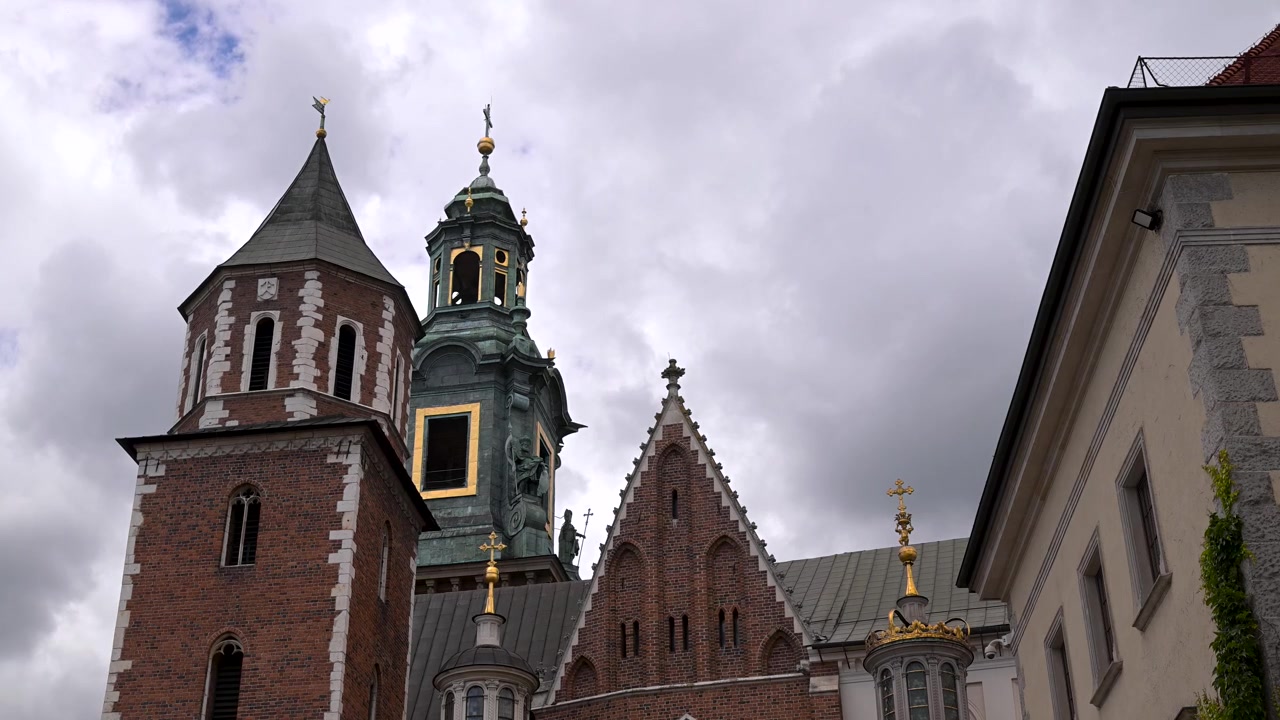 Le storiche torri e il tetto decorato della Cattedrale di Wawel si ergono contro un cielo nuvoloso drammatico a Cracovia, Polonia