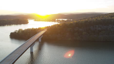 aerial flyover of a car that is driving across a bridge on nickajack lake during the sunset golden hour in tennessee