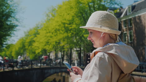 woman uses a smartphone near amsterdam canals