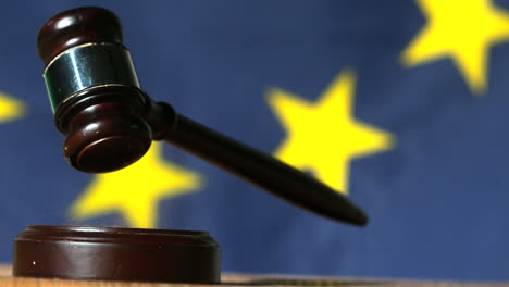 gavel falling onto sounding block with european union flag in background