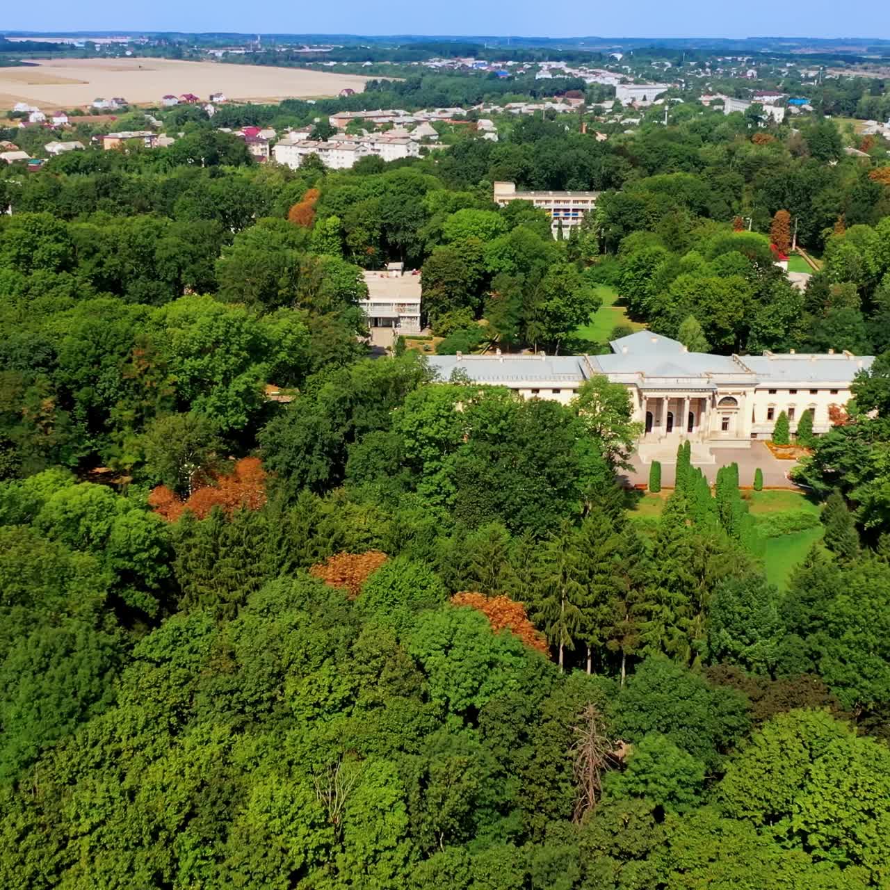 Lush greenery surrounding the beautiful historic palace. Urban landscape and farmlands at backdrop. Top view