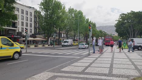 traffic light change to red and pedestrians cross street at funchal city