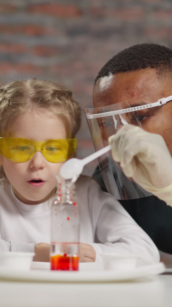 African-American man teacher pours powder while amazed little girl and Asian chemist look at bottle with paint and oil in laboratory slow motion