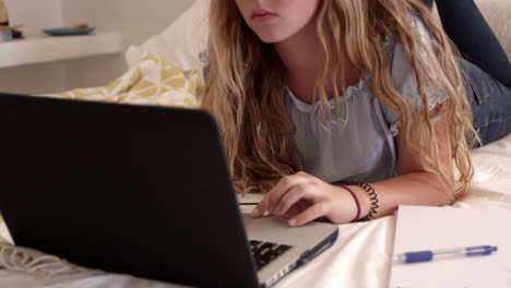 chica adolescente en la cama usando teléfono inteligente y portátil, de cerca, filmado en r3d