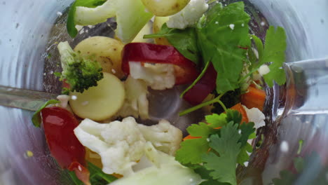 Colorful-vegetables-splashing-blender-close-up-top-view.-Veggies-greens-blending