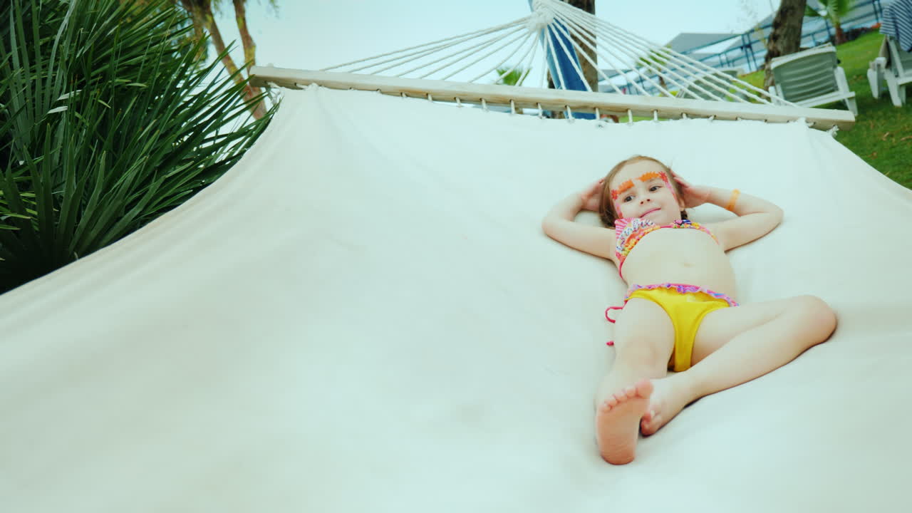 A Little Cool Girl In A Bikini With A Painted Face Rests On A Hammock During The Summer Holidays Free Stock Video Footage Download Clips 