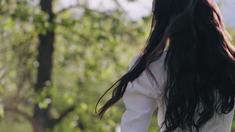 mujer feliz en vestido blanco está caminando en el jardín en flor en la primavera la felicidad y la libertad