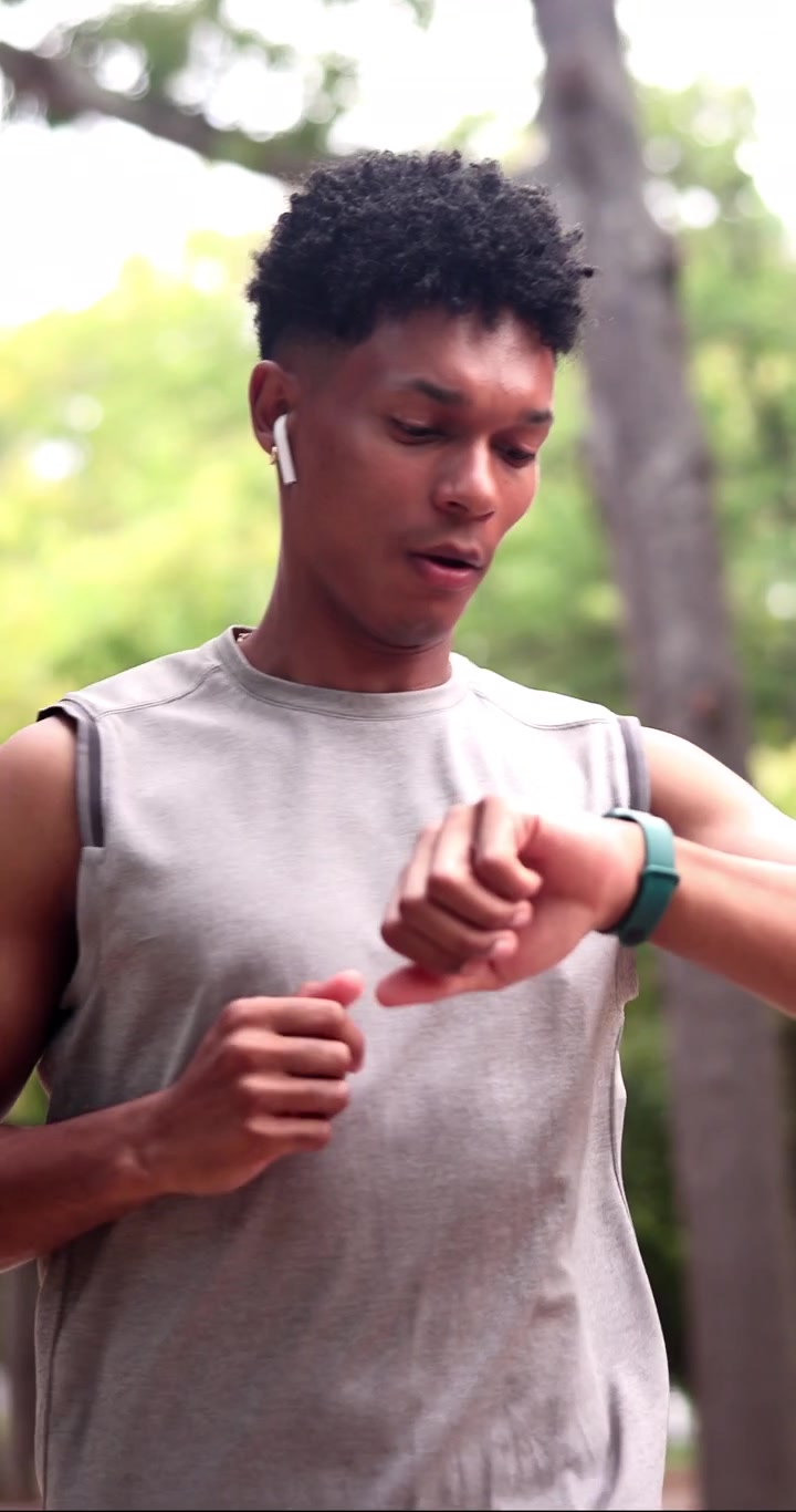 Young Man Jogging in Park and Checking Smartwatch