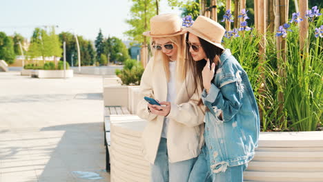 two young women looking at a phone in a park