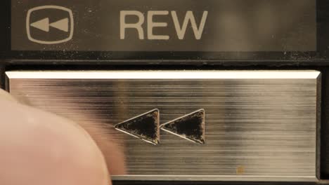 Extreme-close-up-of-buttons-on-an-old-antique-or-vintage-VCR-pushing-the-rewind-button