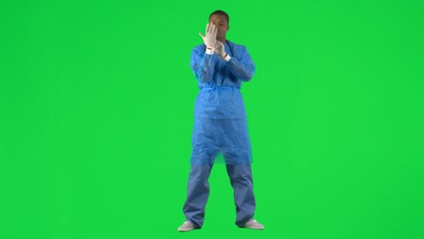 Ethnic-surgeon-putting-on-gloves-against-green-screen