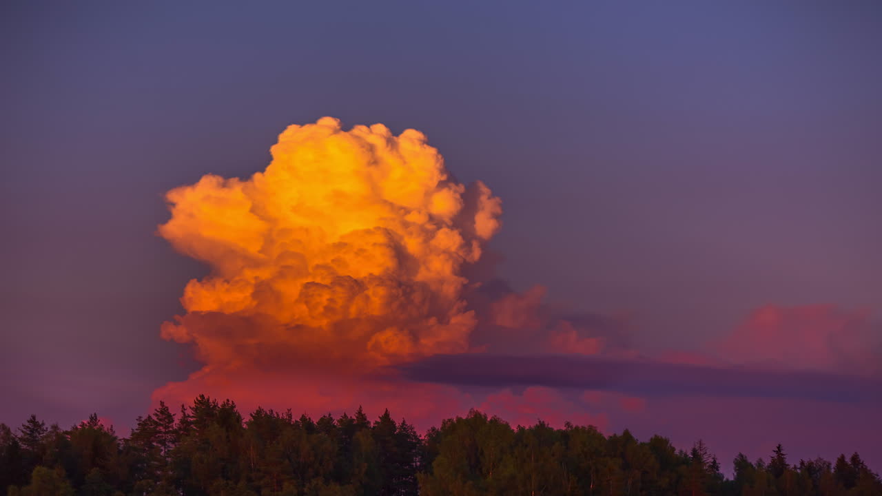 Time lapse of cumulonimbus fiery bomb like clouds in evening sunlight at the sky with forest tree line