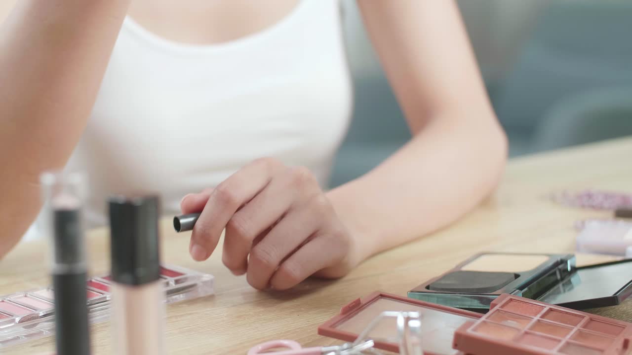 여성 손이 바니티에 아이라이너를 들고 집에서 메이크업을 적용하는 데 사용합니다.