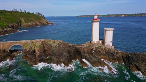 orbital drone shot from left to right around petit minou lighthouse, showing the side path, crashing waves, and rocky cliffs. brittany in france