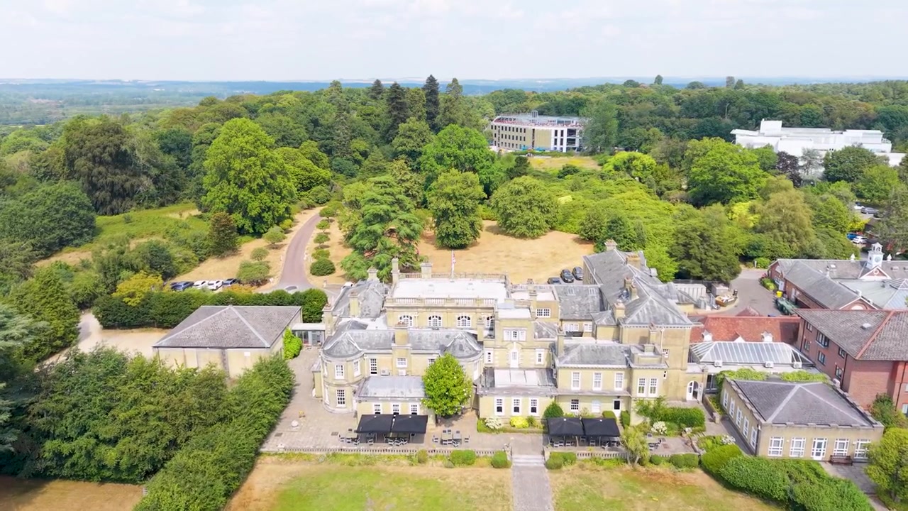 Un drone survole les jardins arrière de Chilworth Manor, passant au-dessus de son toit, en direction des terrains boisés à l'avant, près de Southampton, en Angleterre