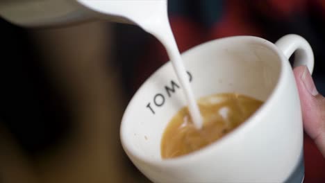 professional barista pouring latte foame over coffee, espresso and creating a perfect cappuccino