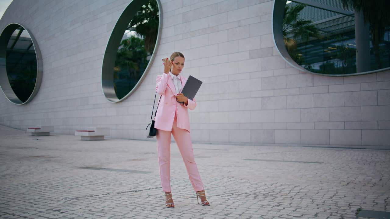 gerente escuchando un mensaje de audio en el teléfono celular de pie cerca del edificio de oficinas.