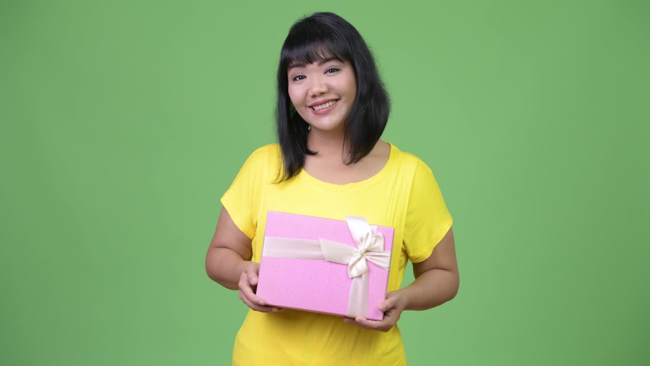 Beautiful Asian woman thinking while holding gift box