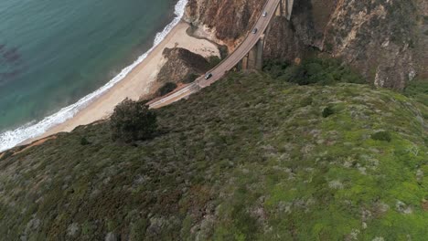 luftdrohnen-stockvideo der autobahn bixby bridge mit wasser und ufer unten in big sur, monterrey, kalifornien