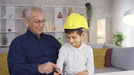 padre e hijo, hijo ayudando a padre a trabajar en casa y mirándolo.