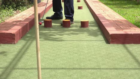 playing mini golf in the sunshine and approaching the hole