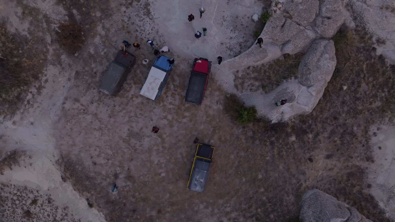 Ripresa drone di veicoli fuoristrada che attraversano una valle rocciosa al tramonto dorato.